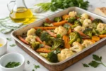 Golden roasted broccoli, cauliflower, and carrots on a baking tray.