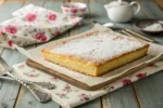 Freshly baked kefir sheet cake with powdered sugar on a rustic table